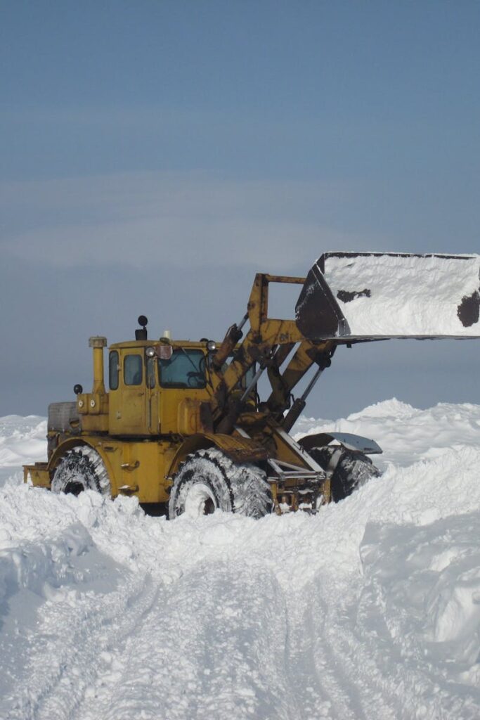 A bulldozer pushes through heavy snow in a winter landscape in Saratov, Russia.