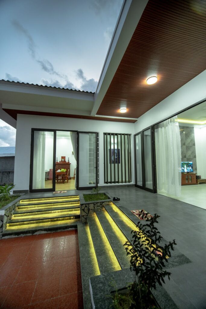 Contemporary house exterior featuring sliding doors and stylish lighting at dusk.