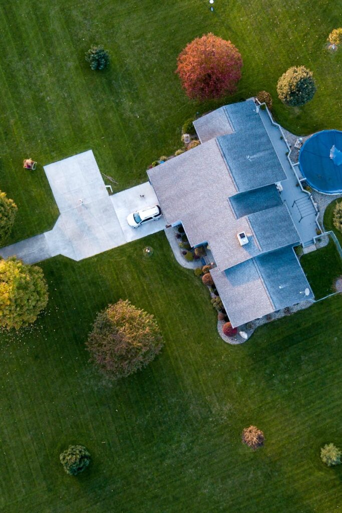 Aerial view of a suburban house with a pool, surrounded by green lawns and autumn trees, in Tipton, Indiana.