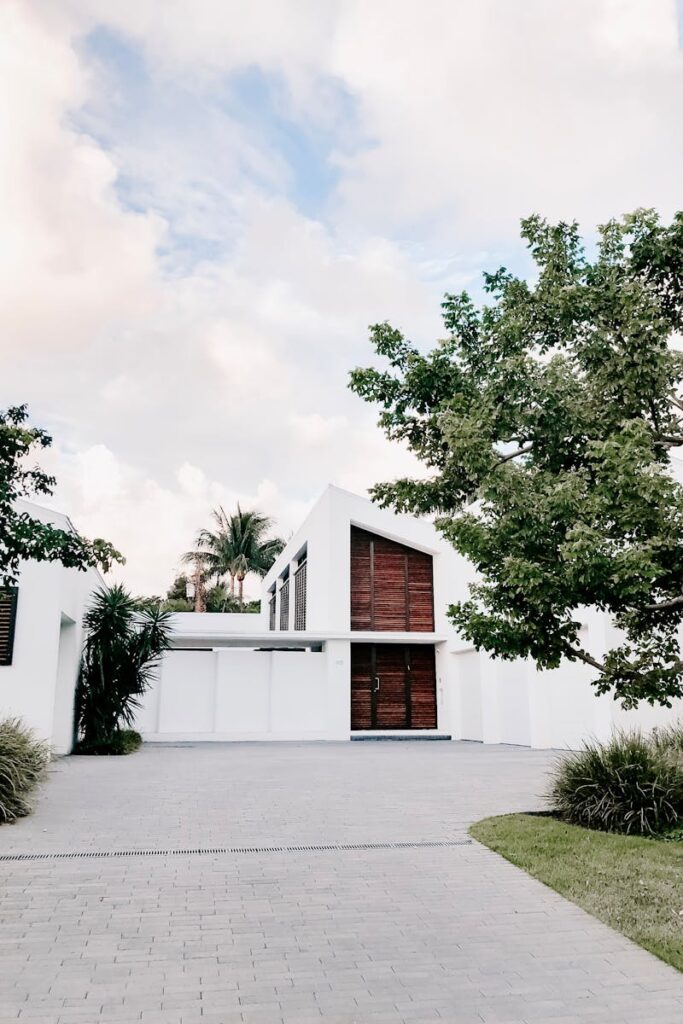 Contemporary minimalist home exterior with lush landscaping and open driveway.