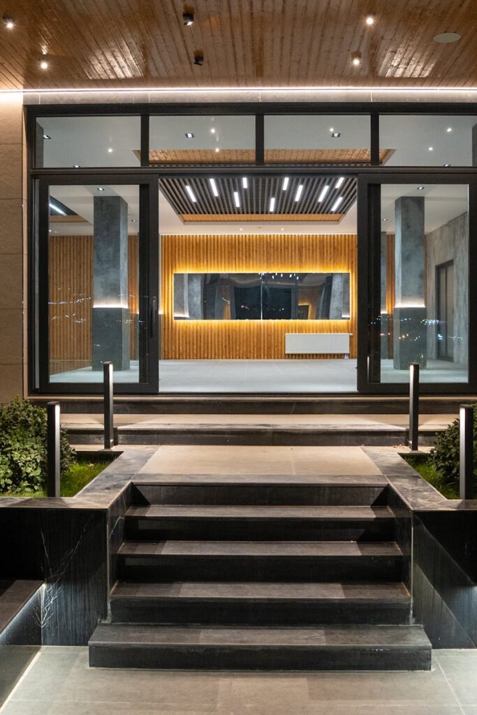 Elegant illuminated entrance to a modern luxury house at night with landscaped garden.