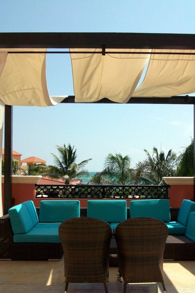 Elegant outdoor seating area on a sunlit rooftop overlooking the ocean.