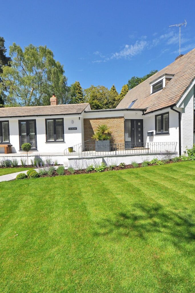 Contemporary house exterior with large manicured lawn and beautiful garden.