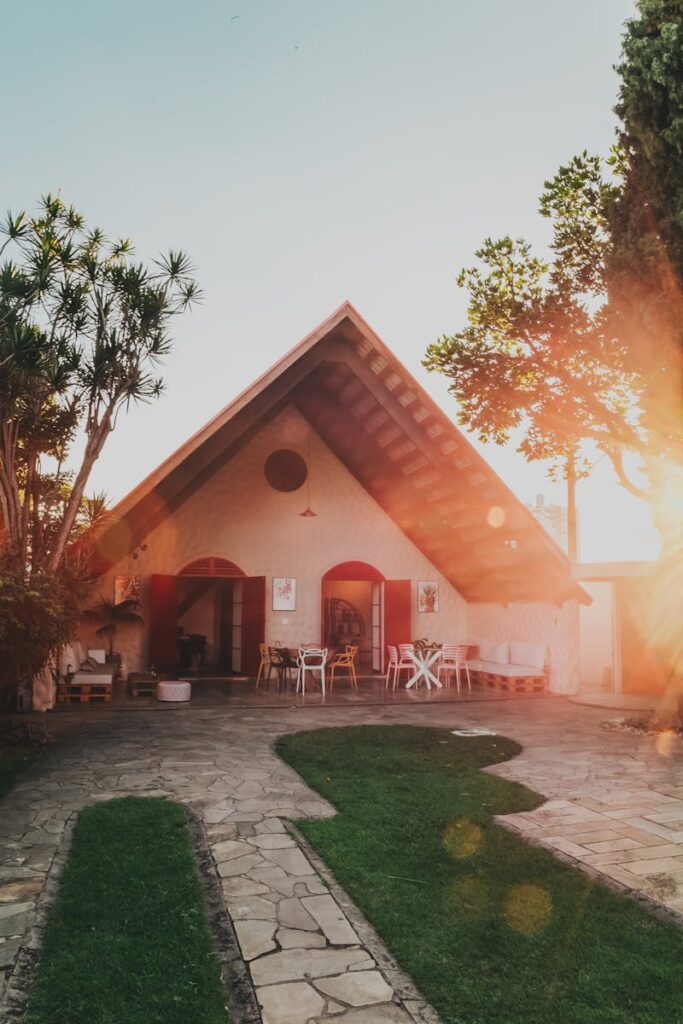 Beautiful A-frame house surrounded by lush garden in warm sunlight, creating a serene and inviting atmosphere.