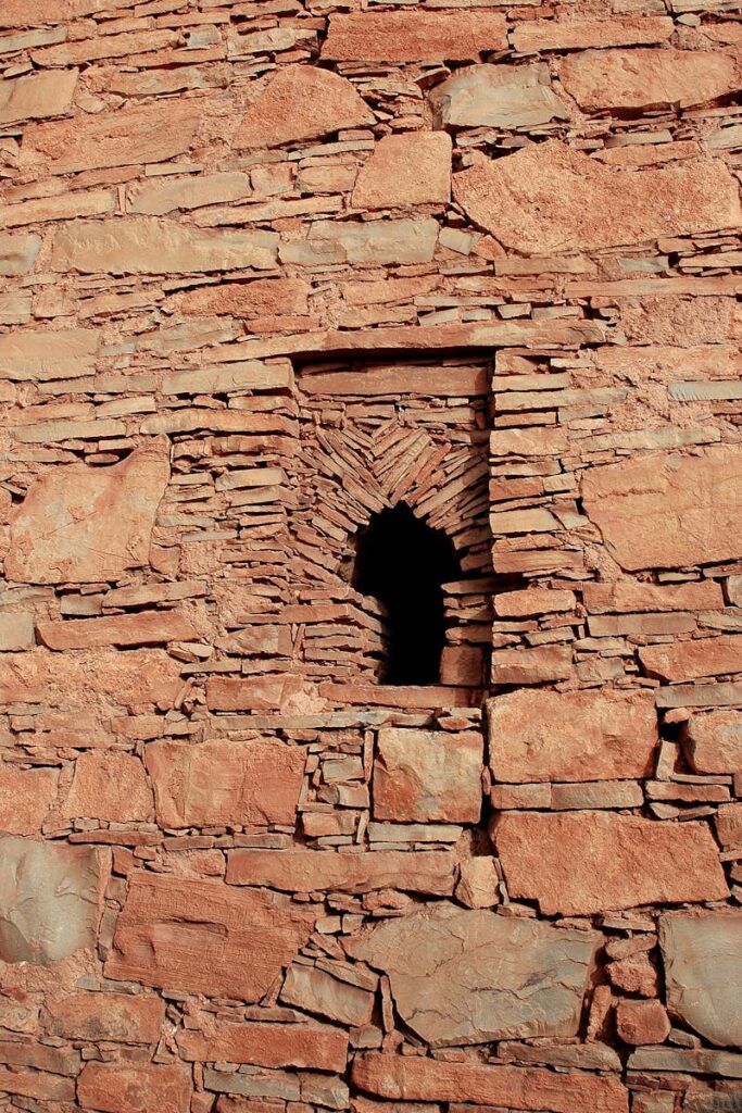 A close-up of a historic stone wall with a unique, narrow window in Tafraoute, Morocco.