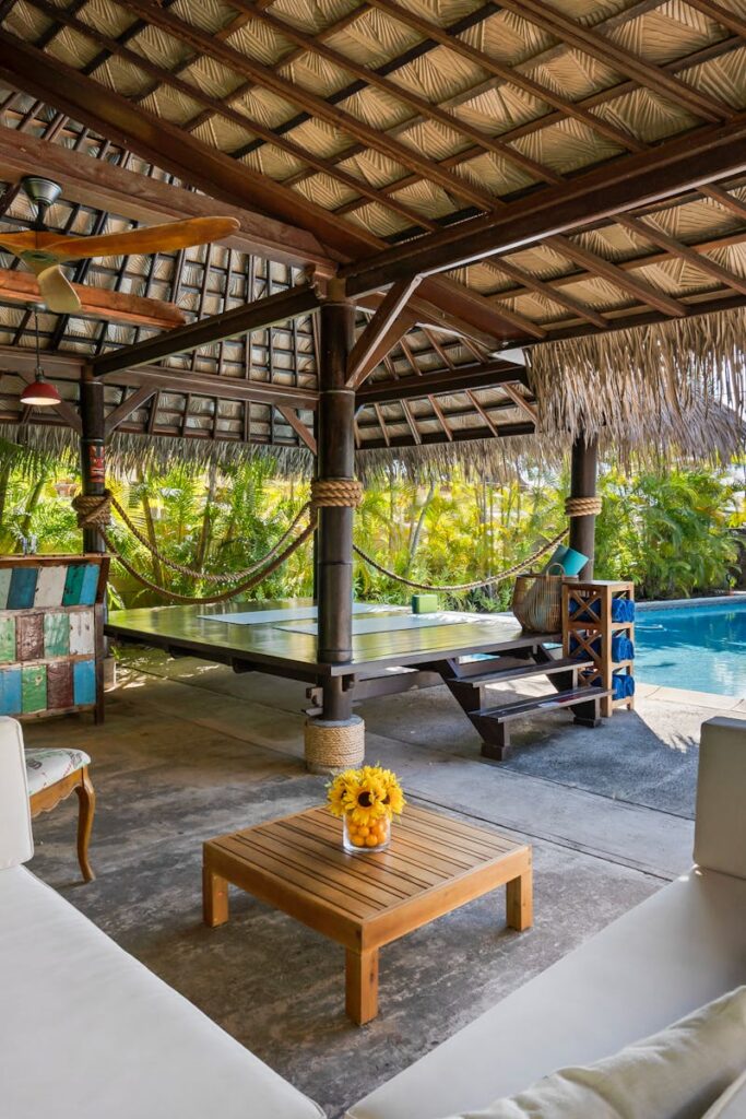 Tropical outdoor patio featuring a cabana, seating area, and swimming pool, perfect for luxury relaxation.