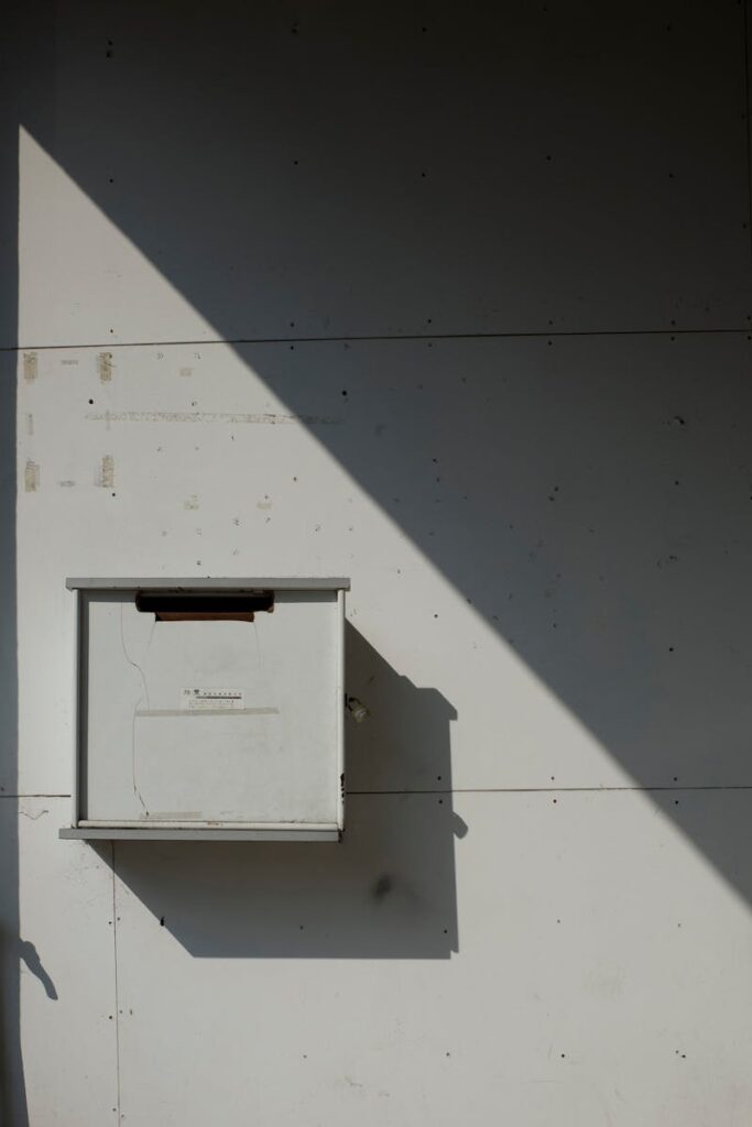 A minimalist mailbox on a wall, highlighted by dramatic light and shadow play.