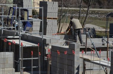 Construction workers building a concrete structure at a sunlit site.