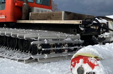 Red snow groomer machine preparing icy slopes for winter sports.